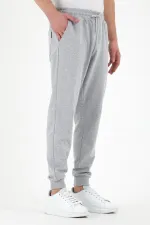 Pantalon de survêtement gris pour homme, coupe classique, avec étiquette, poches arrière et latérales.