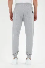 Pantalon de survêtement gris pour homme, coupe classique, avec étiquette, poches arrière et latérales.