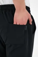 Pantalon de survêtement noir pour homme, coupe classique, avec étiquette, poches arrière et latérales.