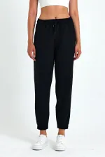 Pantalon de jogging confortable en coton épais noir pour femme, avec ourlet élastiqué et poches.