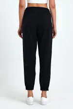 Pantalon de jogging confortable en coton épais noir pour femme, avec ourlet élastiqué et poches.