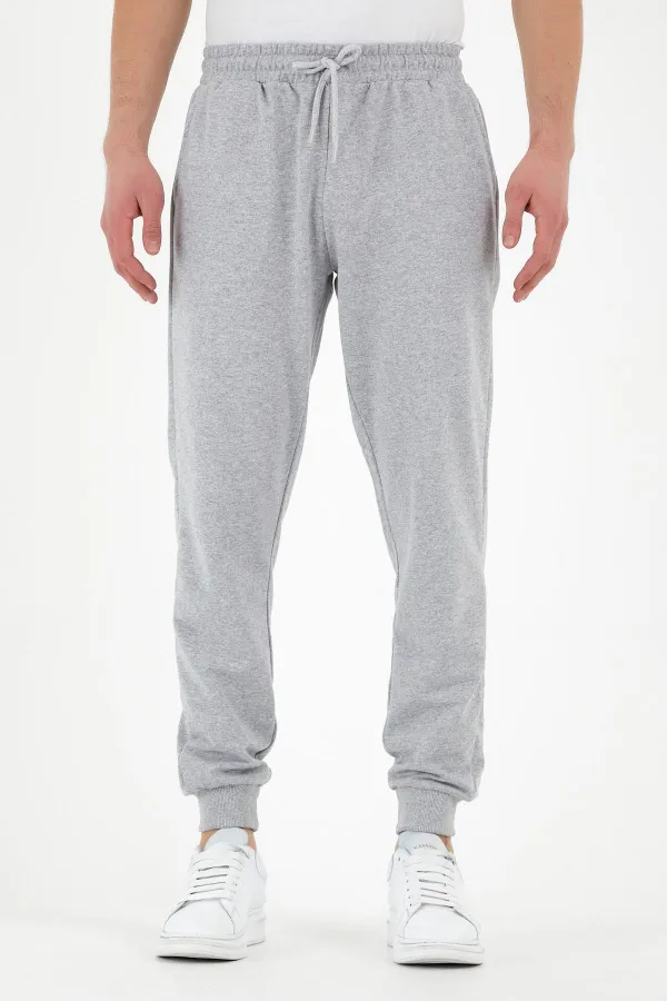 Pantalon de survêtement gris pour homme, coupe classique, avec étiquette, poches arrière et latérales.