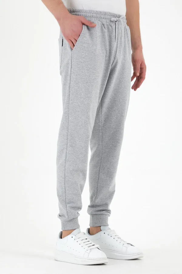 Pantalon de survêtement gris pour homme, coupe classique, avec étiquette, poches arrière et latérales.