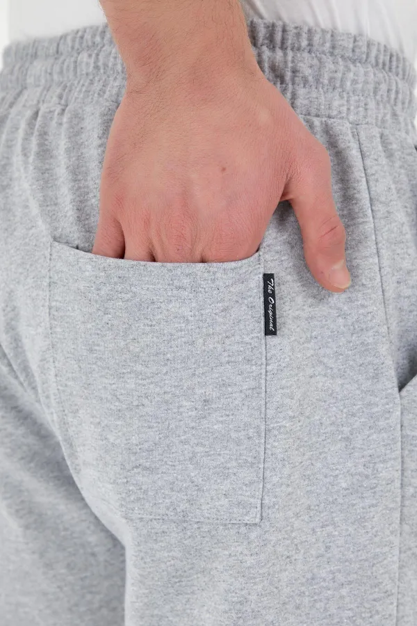 Pantalon de survêtement gris pour homme, coupe classique, avec étiquette, poches arrière et latérales.