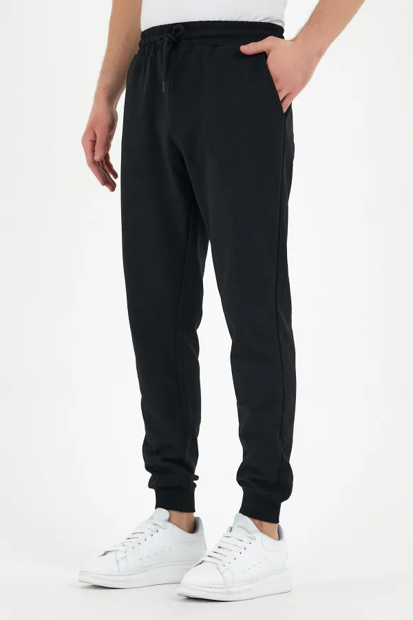 Pantalon de survêtement noir pour homme, coupe classique, avec étiquette, poches arrière et latérales.