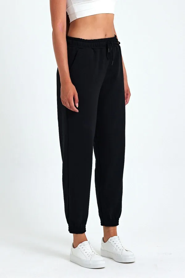 Pantalon de jogging confortable en coton épais noir pour femme, avec ourlet élastiqué et poches.