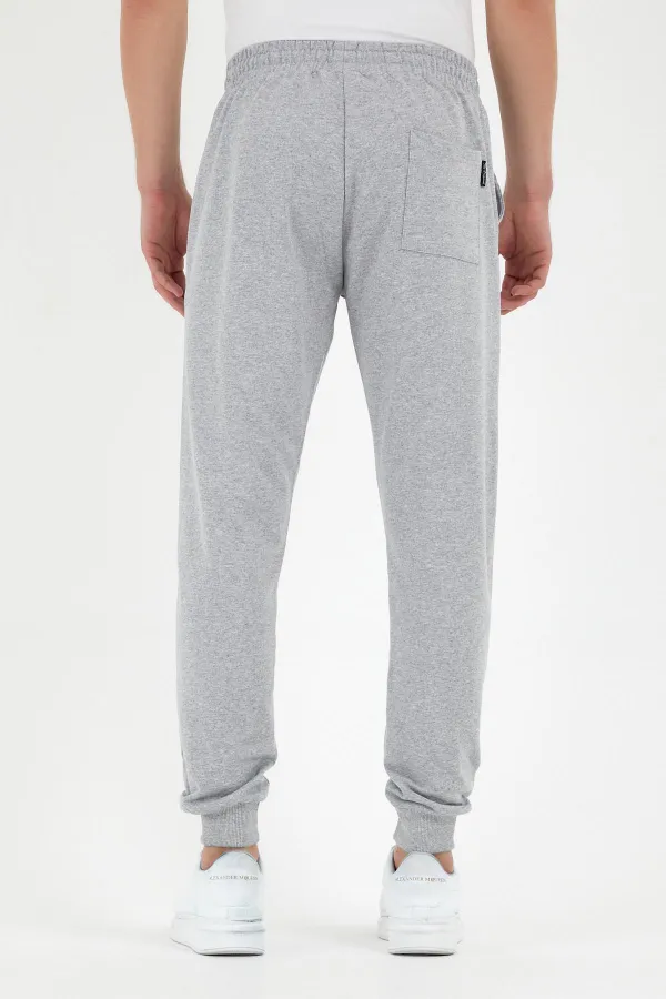 Pantalon de survêtement gris pour homme, coupe classique, avec étiquette, poches arrière et latérales.