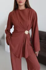 Ensemble chemisier et pantalon avec broche dorée.