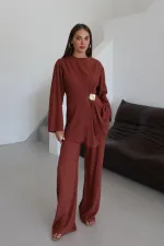 Ensemble chemisier et pantalon avec broche dorée.