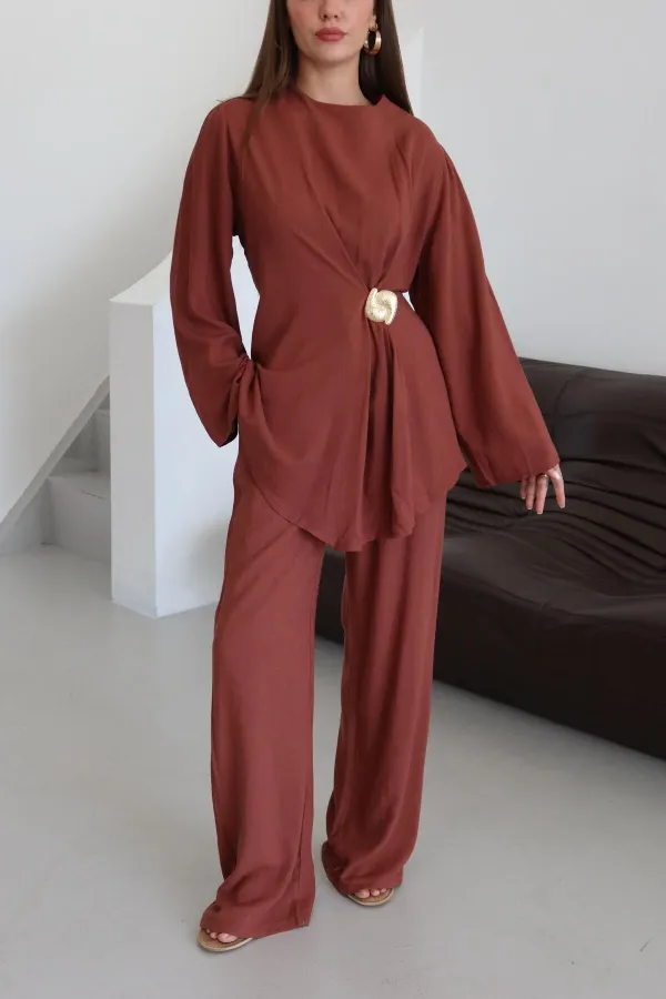 Ensemble chemisier et pantalon avec broche dorée.