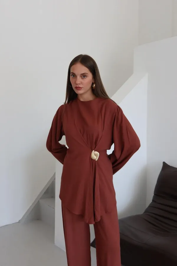 Ensemble chemisier et pantalon avec broche dorée.