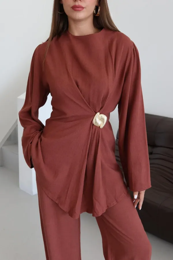 Ensemble chemisier et pantalon avec broche dorée.