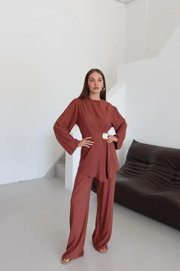 Ensemble chemisier et pantalon avec broche dorée.