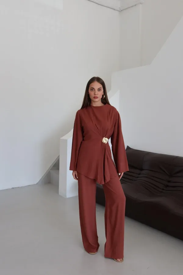 Ensemble chemisier et pantalon avec broche dorée.