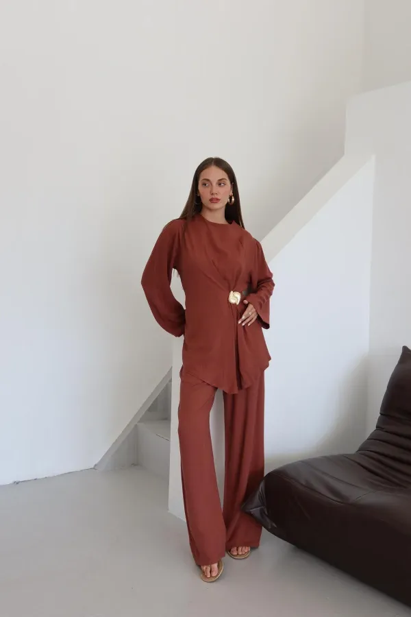 Ensemble chemisier et pantalon avec broche dorée.