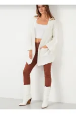 Gilet en maille ample pour femme, avec manches repliées et poches.