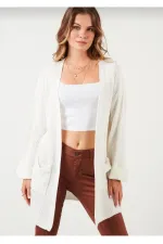 Gilet en maille ample pour femme, avec manches repliées et poches.