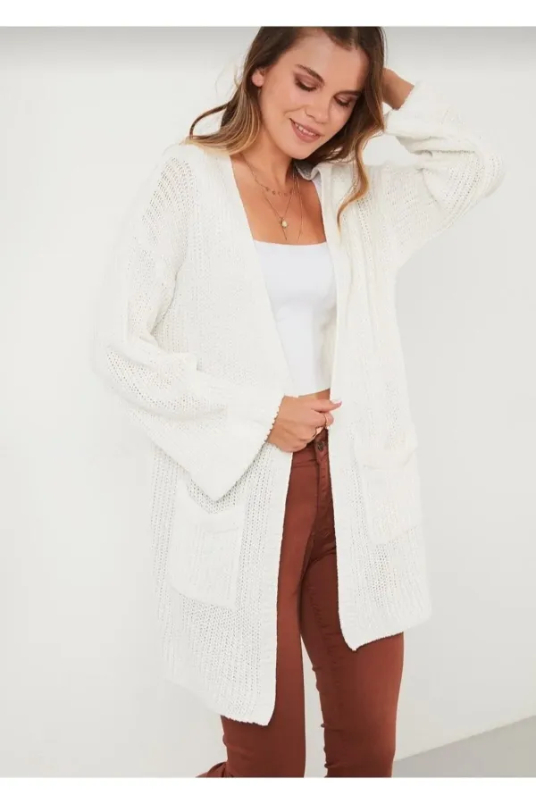 Gilet en maille ample pour femme, avec manches repliées et poches.