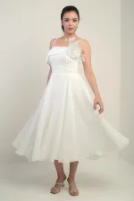 Robe à bretelles croisées dans le dos, lacée, à une manche tombante, ornée d'une broche en plumes et doublée en tissu brillant.