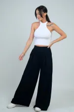 Pantalon Osyho pour femme, jambes larges, taille élastique, poches et plis sur le devant.