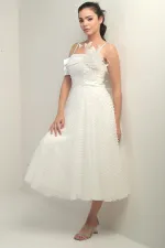 Robe à bretelles croisées dans le dos, lacée, à une manche tombante, ornée d'une broche en plumes et doublée en tissu brillant.