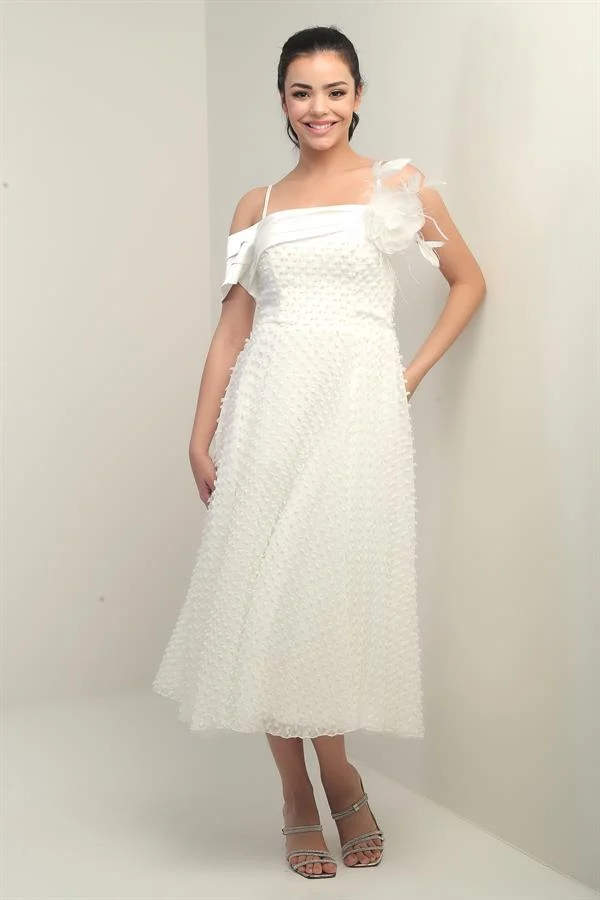 Robe à bretelles croisées dans le dos, lacée, à une manche tombante, ornée d'une broche en plumes et doublée en tissu brillant.