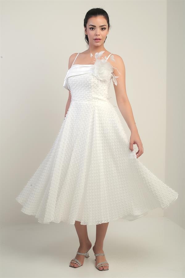 Robe à bretelles croisées dans le dos, lacée, à une manche tombante, ornée d'une broche en plumes et doublée en tissu brillant.