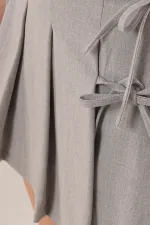 Jupe courte grise en gros avec plis sur le devant et nœud sur le côté