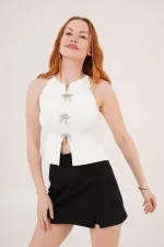 Chemisier blanc en gros avec détail de broche en nœud laqué et manches zéro