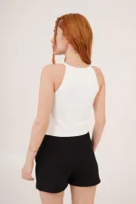 Chemisier blanc en gros avec détail de broche en nœud laqué et manches zéro