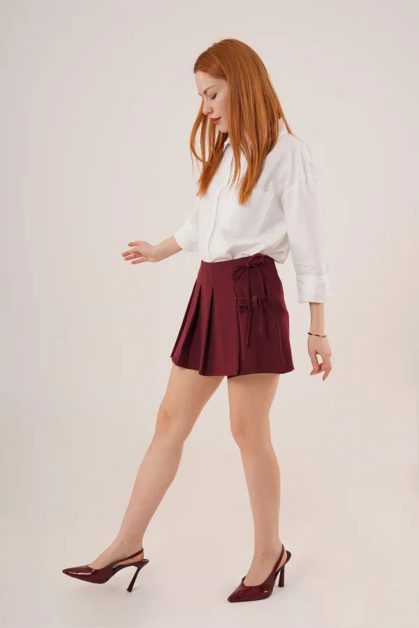 Mini-jupe courte bordeaux en gros avec devant plissé et détails de cravate sur le côté