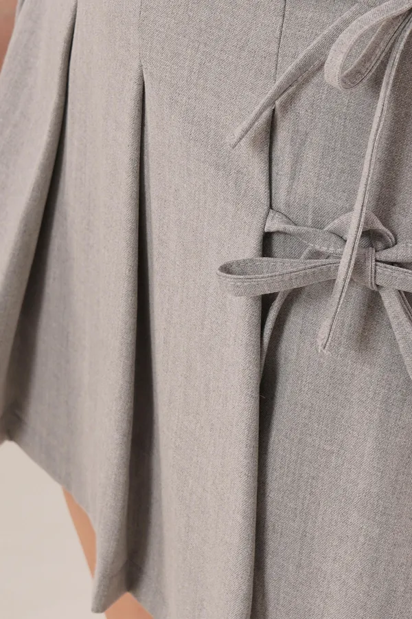 Jupe courte grise en gros avec plis sur le devant et nœud sur le côté