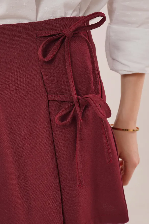 Mini-jupe courte bordeaux en gros avec devant plissé et détails de cravate sur le côté